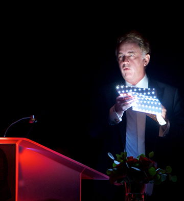 EMC photo of CEO and President Jerry Johnson standing at podium with LED lighting 